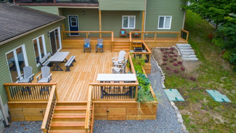 a deck with chairs and tables on it next to a house